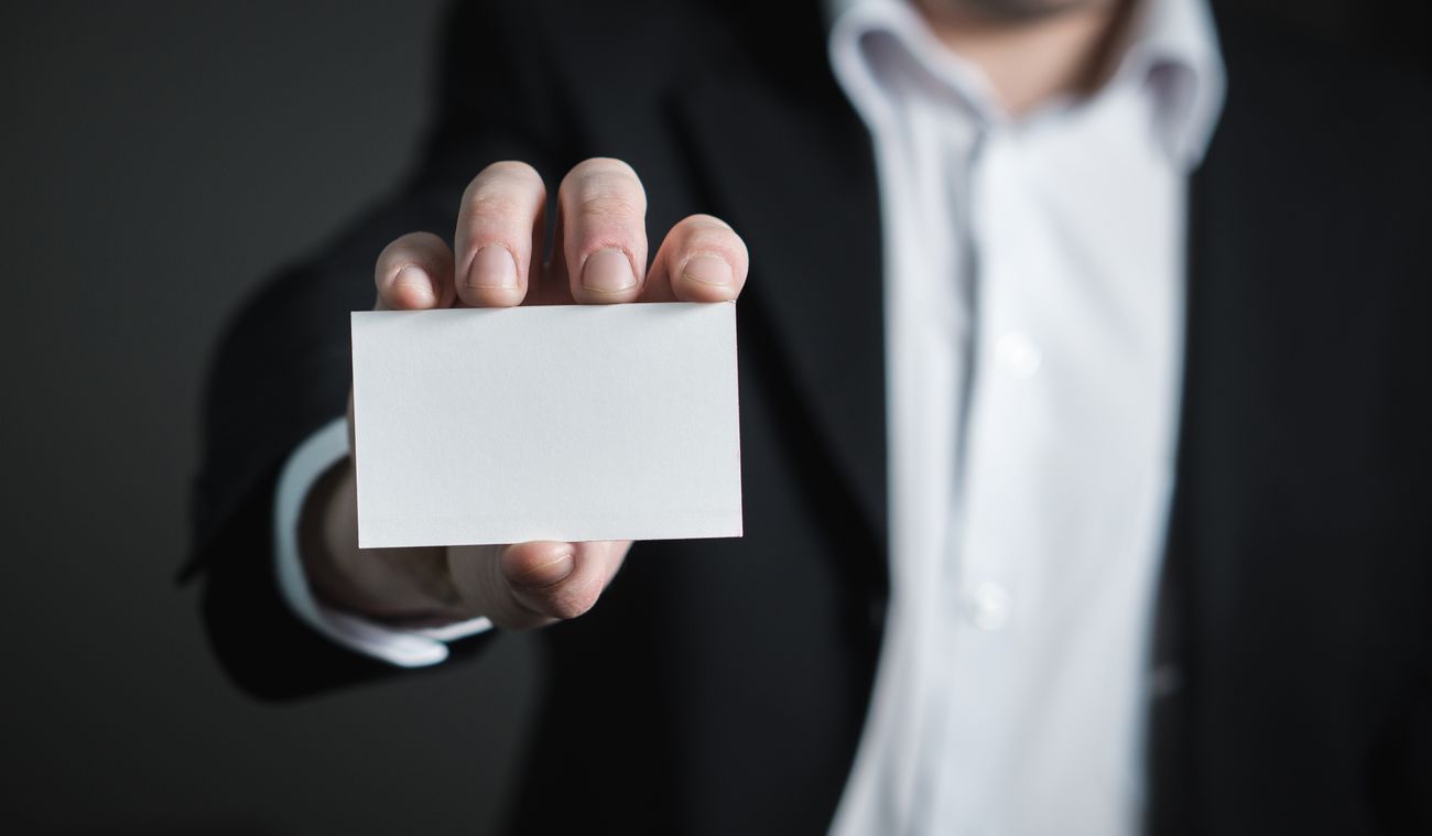 A hand holding out a blank business card