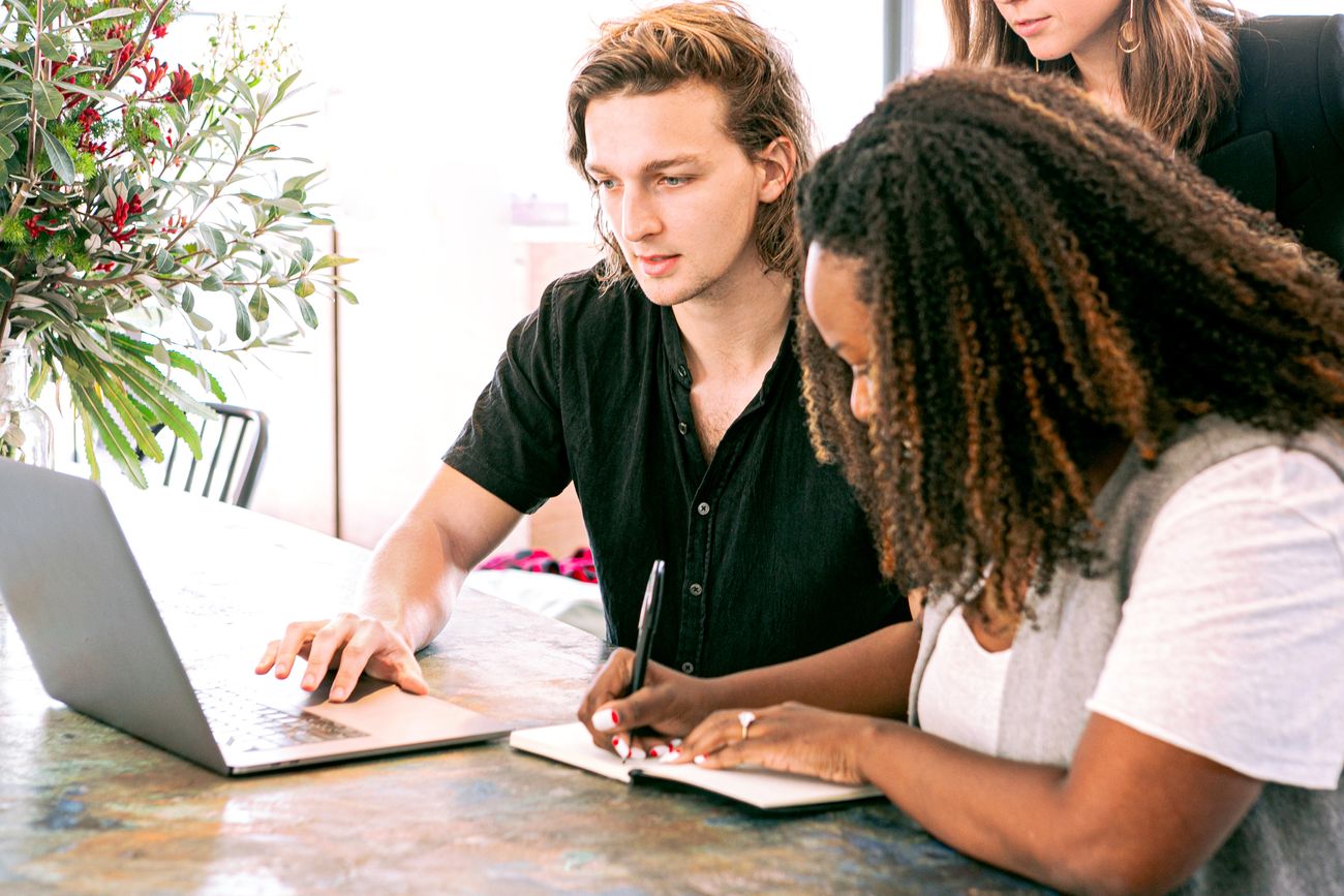 A small team working together at a laptop and notebook